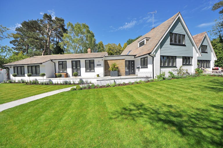 Contemporary house exterior with large manicured lawn and beautiful garden.