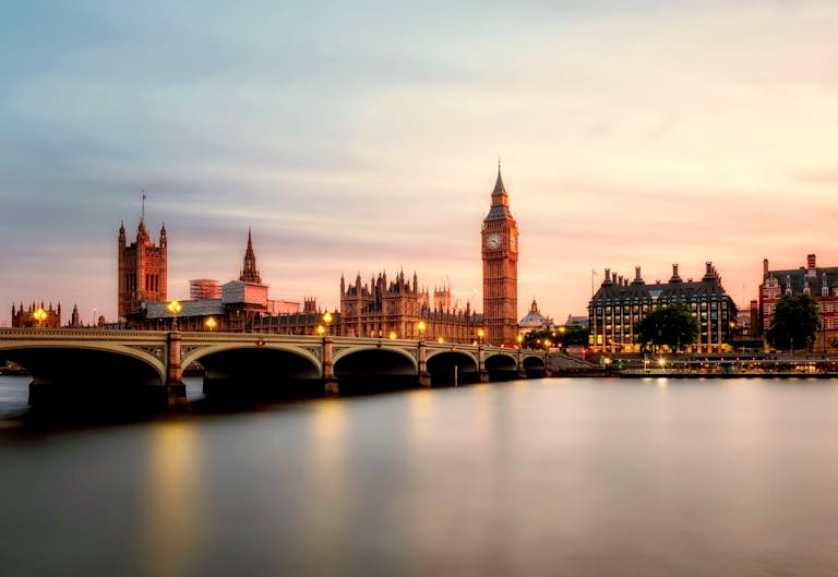 Scenic view of Big Ben and Westminster Bridge over the Thames River at sunset in London, UK.